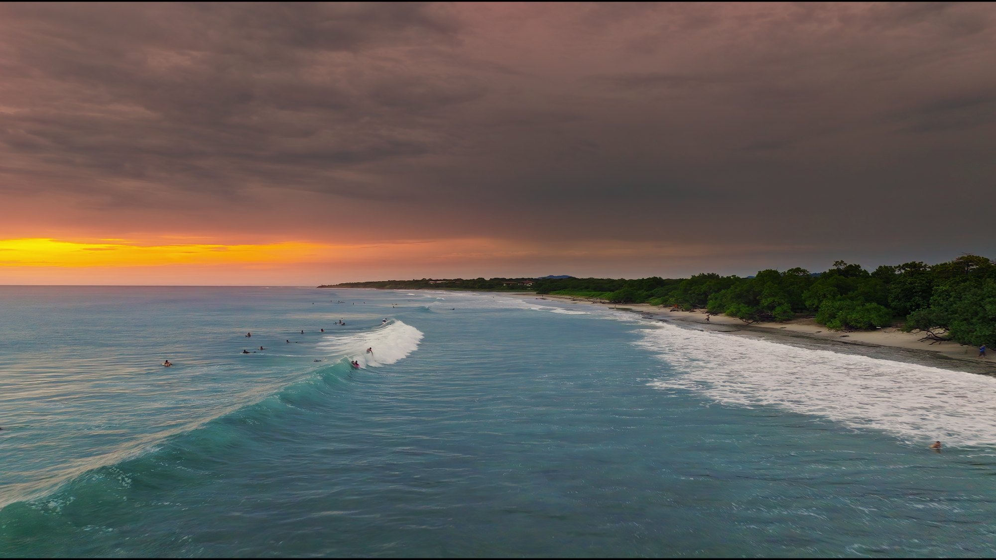 Surfers riding waves at sunset on a Pacific coast beach in Guanacaste, Costa Rica